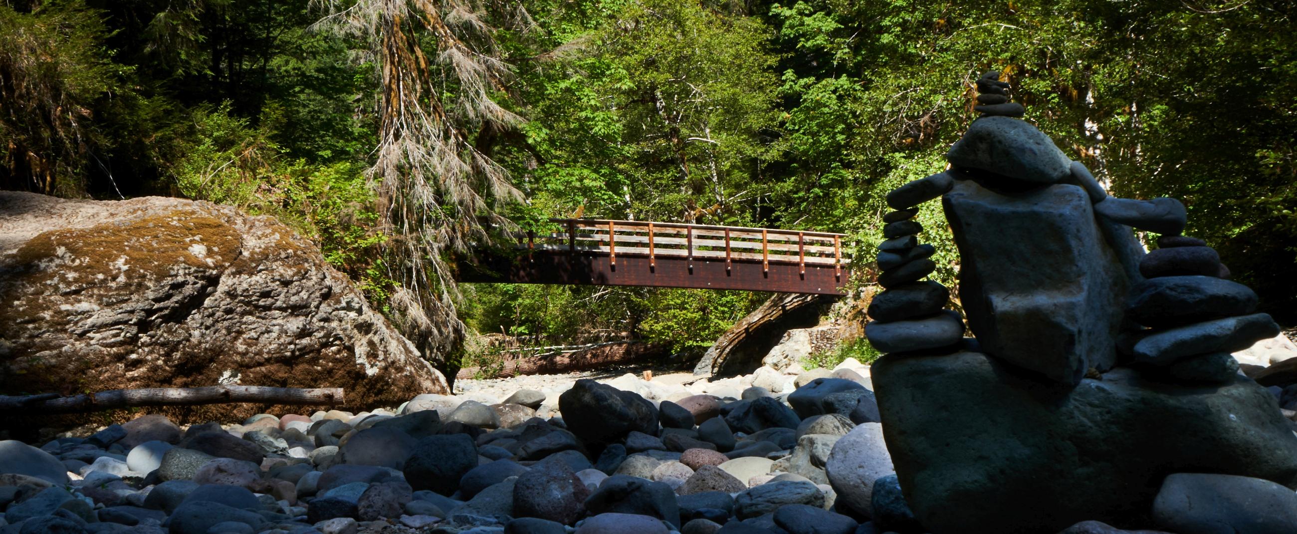 View of wooden bridge with a stack of rocks in the foreground